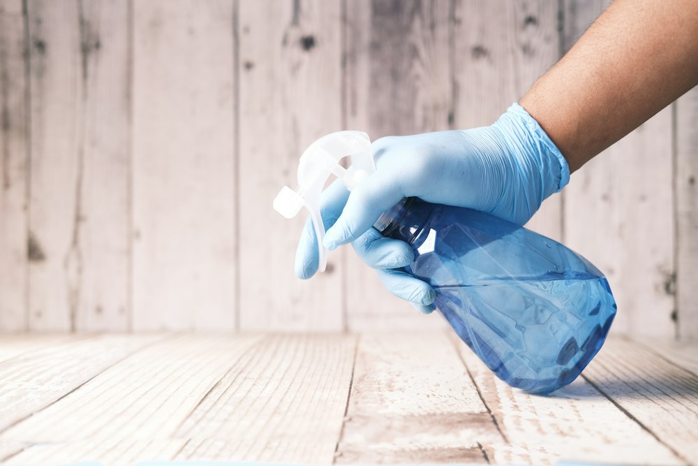 Hand i handske som sprayar rengöringsmedel